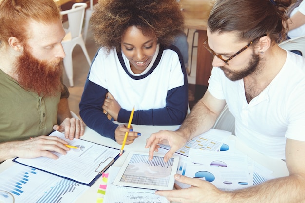 A diverse group of people looking at a projected graph showing tax rates and debt reduction, with expressions ranging from concern to hope.