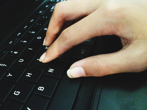 A person's hands typing on a computer keyboard. The focus is on the fingertips pressing specific keys, highlighting the act of data entry. The background is blurred, creating a sense of depth and drawing attention to the hands. The laptop screen displays the FAFSA website, indicating the context of the typing activity.