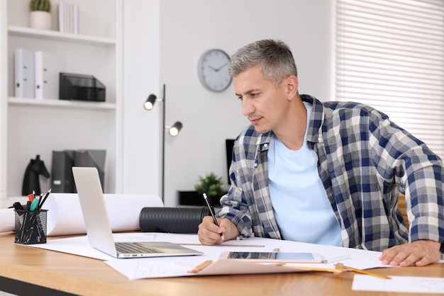 A person working on a budget spreadsheet on a laptop, with various financial documents and a calculator on the desk. The scene conveys careful planning and attention to detail in managing finances.
