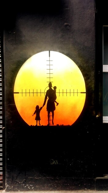 A split image showing contrasting scenes: on one side, a family being reunited at an airport immigration gate; on the other side, a person standing alone behind a chain-link fence at a border.