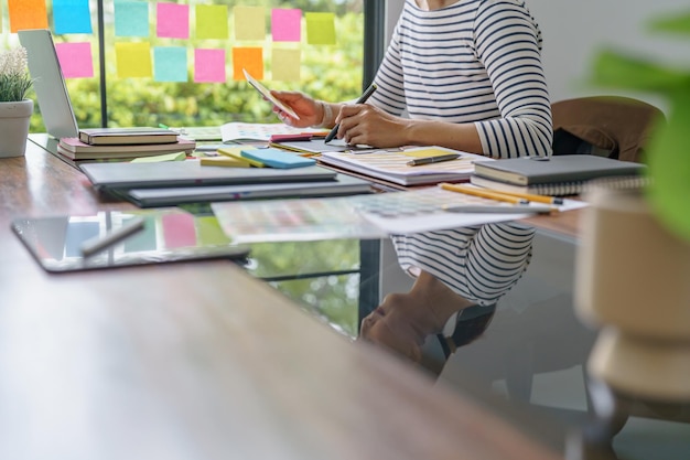 A person working on a laptop in a modern, collaborative office space, with sticky notes and diagrams on a whiteboard in the background, symbolizing the adaptability required for modern problem solving.